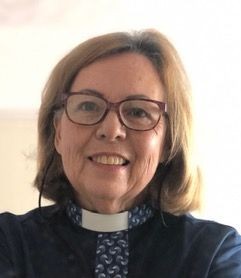 Mtr Jenny Krige, wearing a clerical collar, smiling