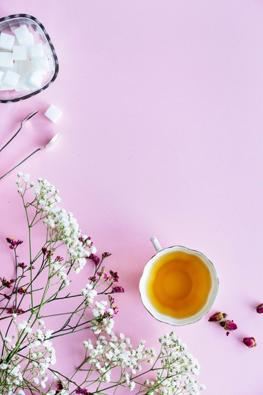 Flat-lay of a cup of tea with sugar cubes and small flowers