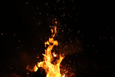 Sparks and flames rising from a bonfire at night