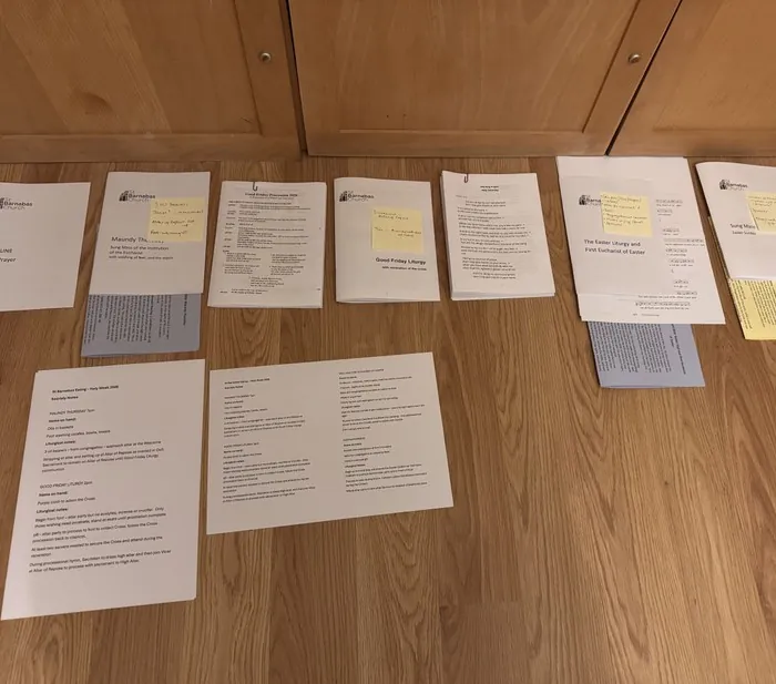Printed Holy Week service booklets laid out on a wooden floor for checking