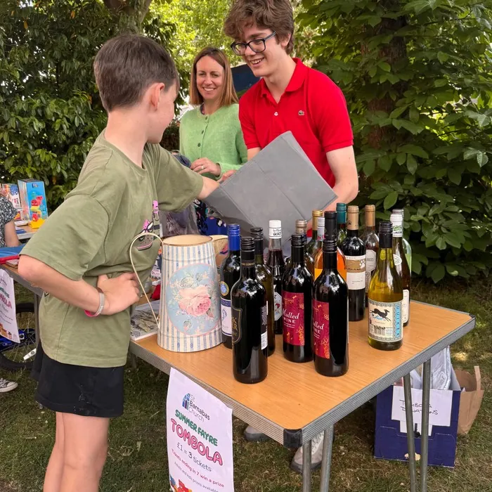 A boy buys a raffle ticket at the tombola stall's table of bottles