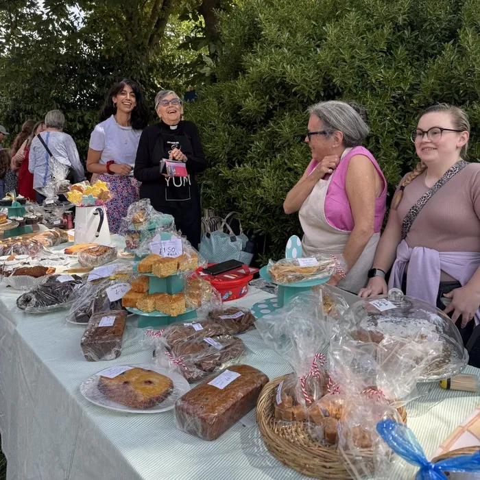 Volunteers stand behind a table of cakes and baked goods at the Fayre