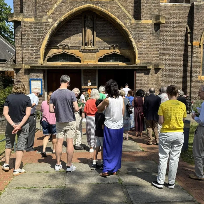 A crowd queues to enter the church on a sunny morning