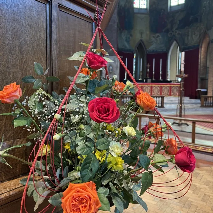 A red and orange flower arrangement in the church, with the altar behind