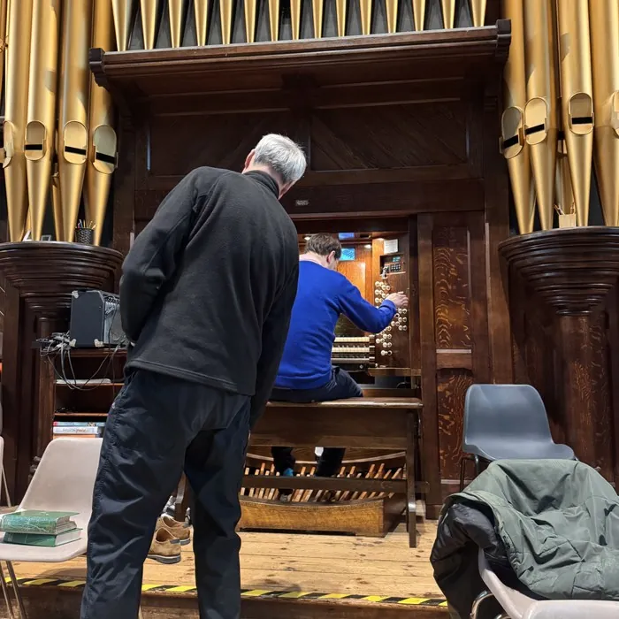 Nick working inside the pipe organ console with a colleague