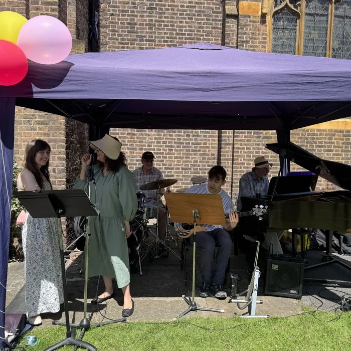 A band playing under a gazebo, with balloons overhead, at the Summer Fayre