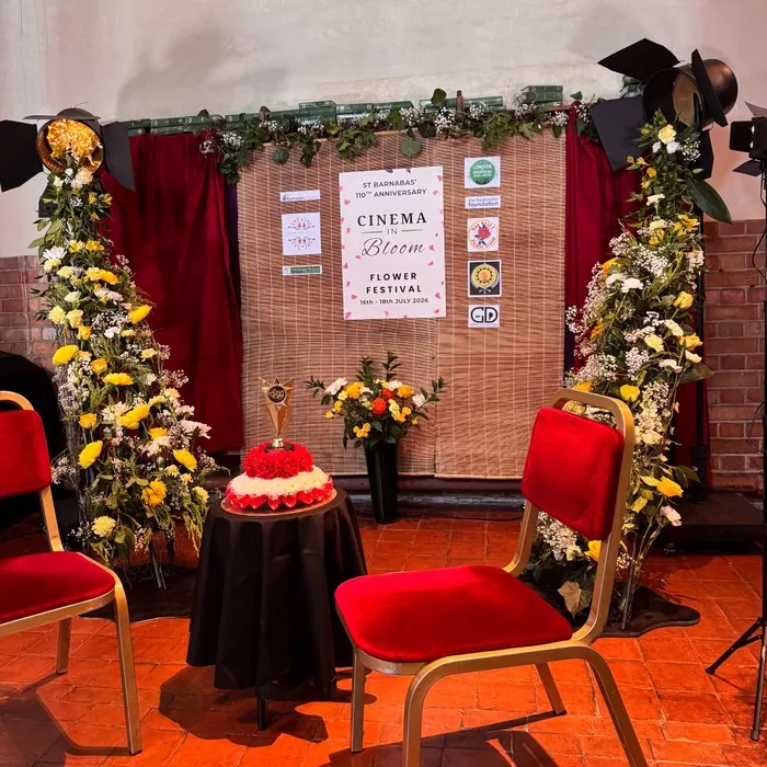 Flower Festival stage decorated with yellow and white floral arches beside red chairs