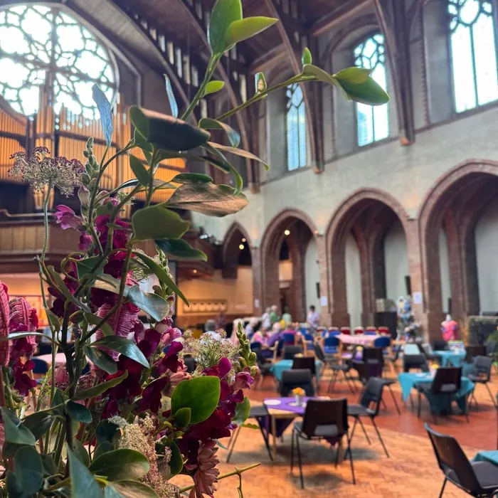 A dark red and white floral display overlooking tables set out in the hall