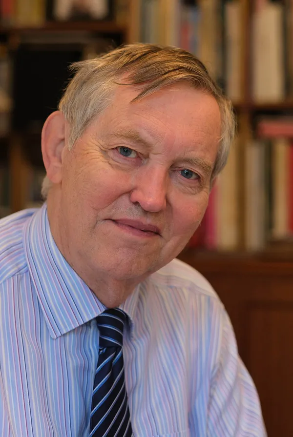 Hugh Mather in a striped shirt and striped tie, photographed in his study