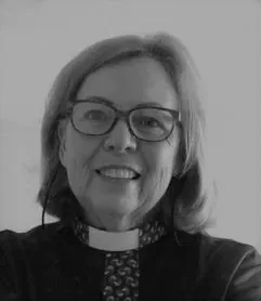 Mother Jenny smiling in glasses and a clerical collar, in a black-and-white photograph