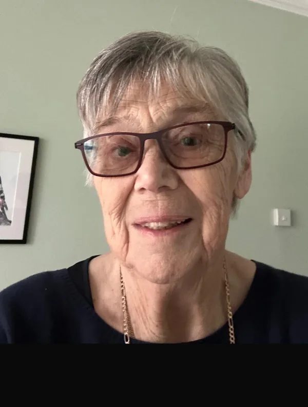 Mother Valerie smiling, in glasses and a navy top with a gold chain